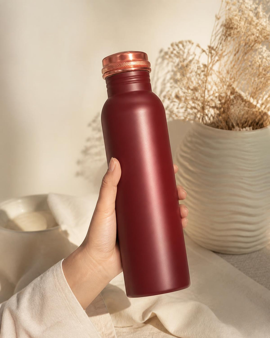 Maroon copper bottle held in hand